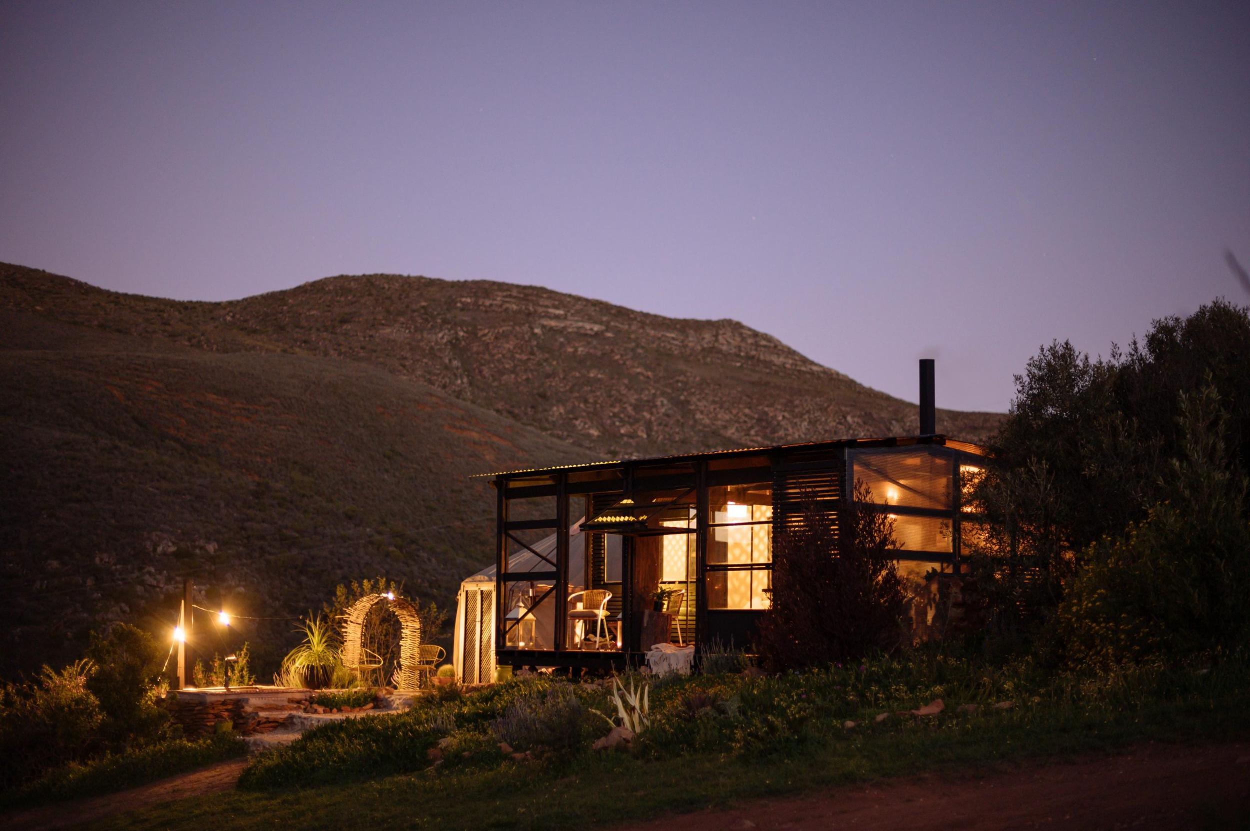 Southern Yurts: Glowing cabin lit at blue-hour dusk against dark mountain