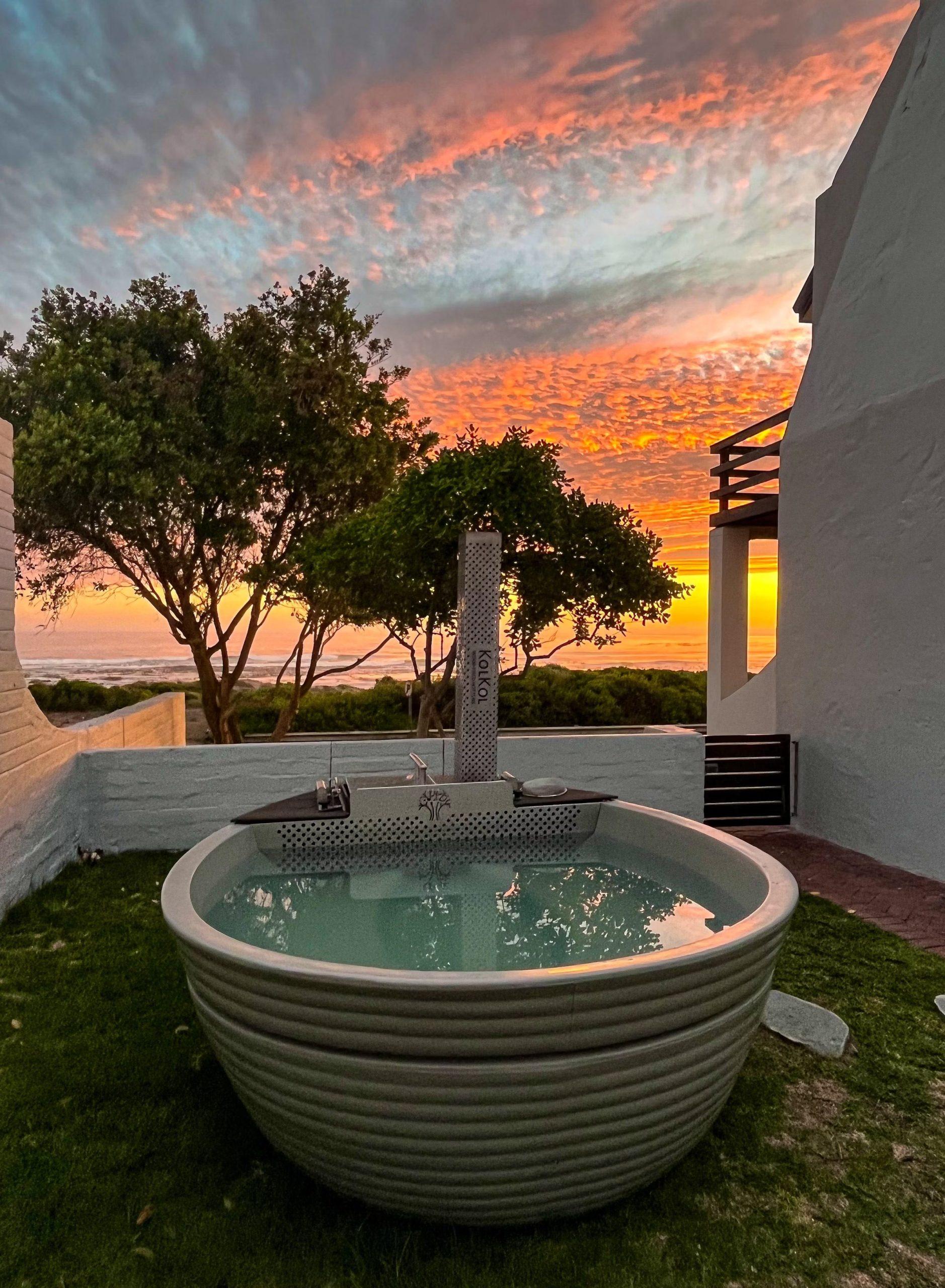 Storkereden: Round hot tub against fiery orange sunset over ocean