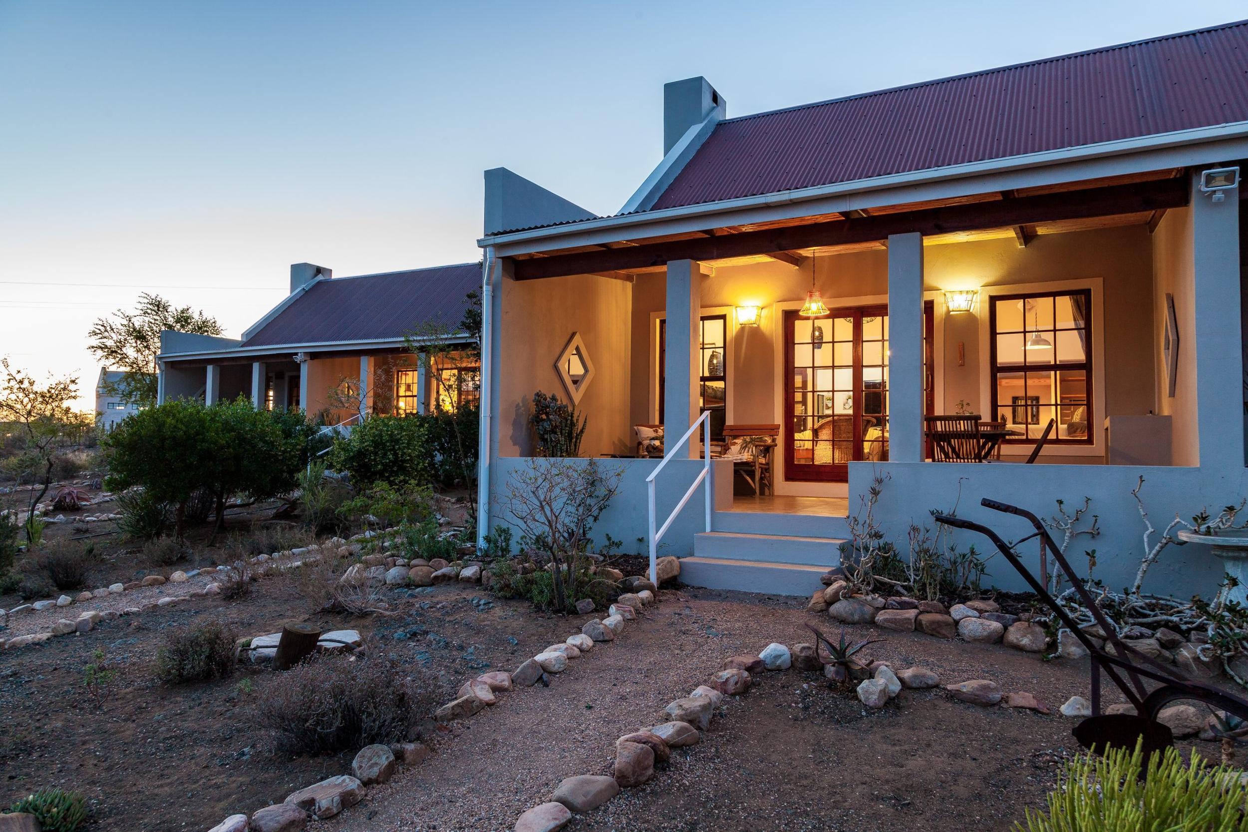 Kanon Cottage at Karoo View: Lit cottage facade with fire pit, lavender and wicker chairs