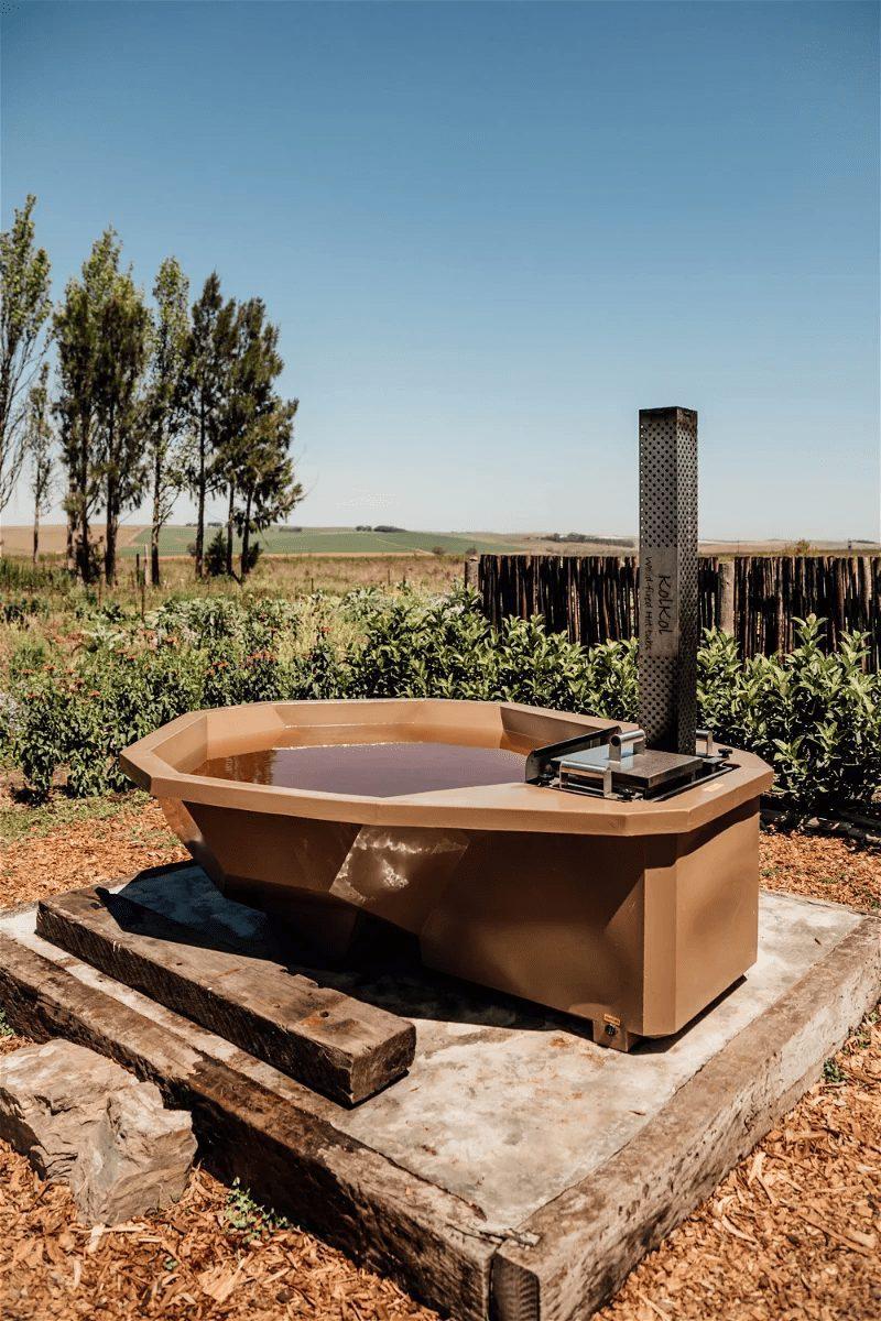 Aloe Cottage at Bokrivier: Wood-fired hot tub with chimney heater on open farmland under blue sky