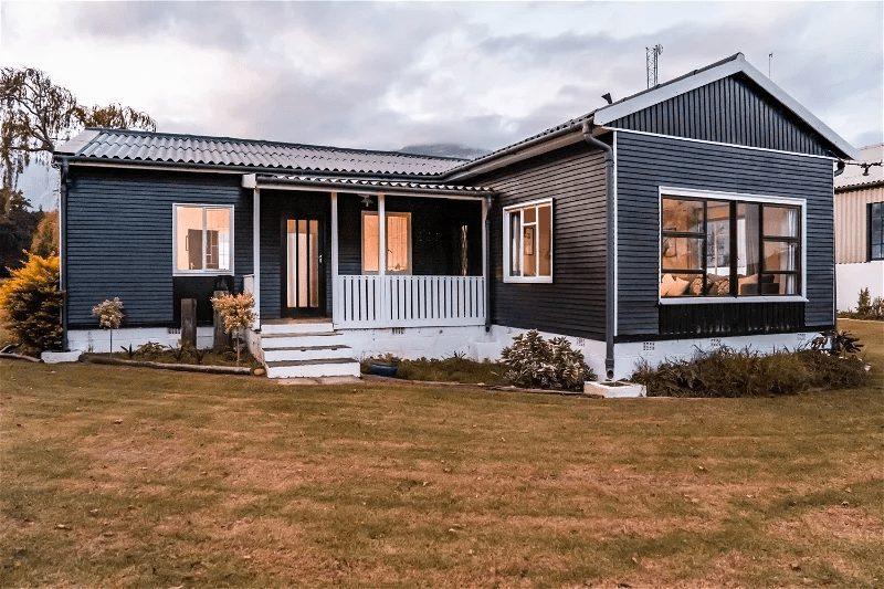 Blombos Cottage at Bokrivier: Dark cabin at dusk, glowing windows, moody cloudy sky