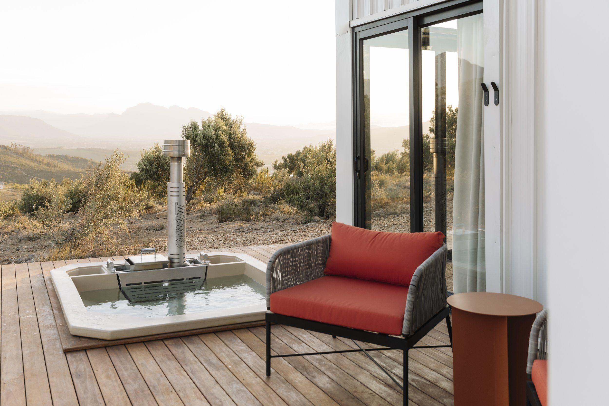 Hemingway Eco Pod: the sunken wood-fired hot tub on the deck at golden hour, looking over the Winelands valley