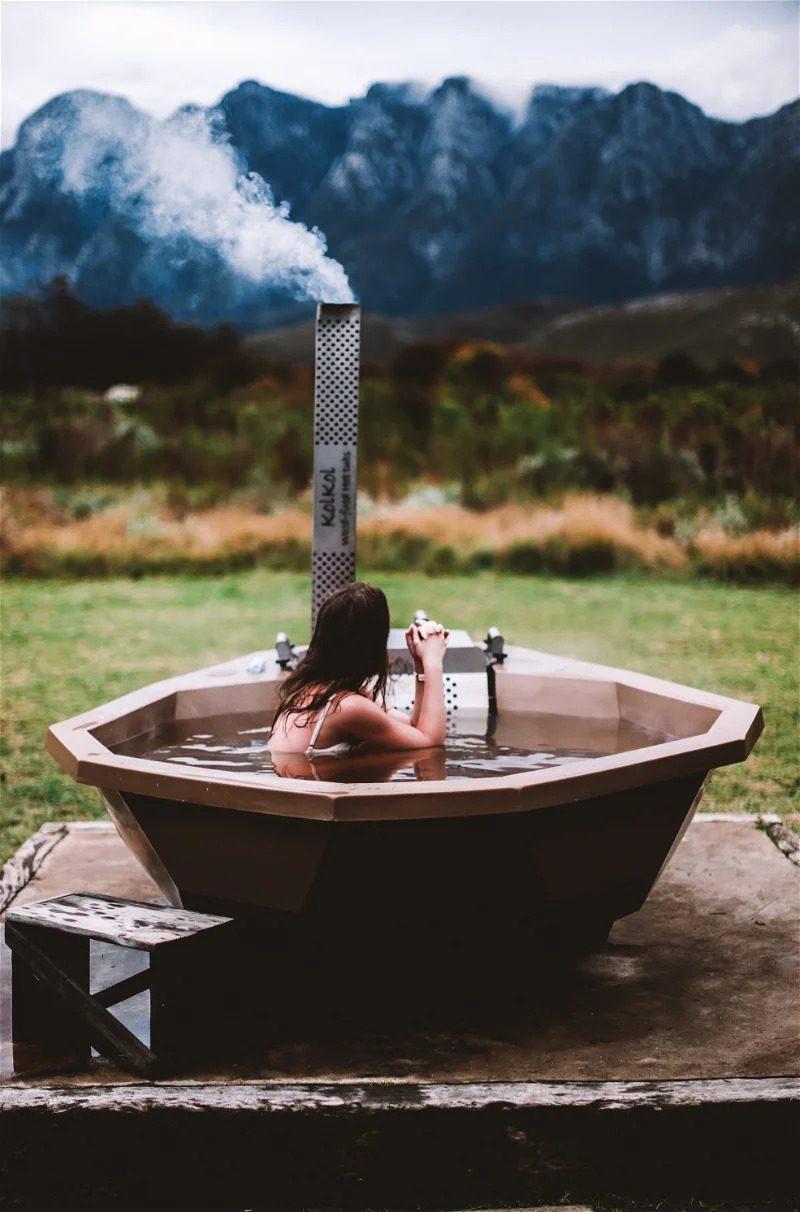 Kolkol Cottage at Bokrivier: Woman in steaming wood-fired hot tub before misty mountains