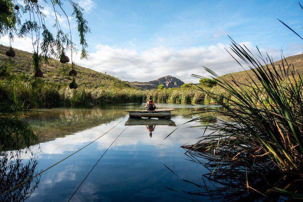 Forest View Yurt: Person in canoe on still dam, mountains and reflections
